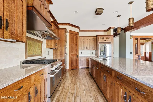 a kitchen with stainless steel appliances granite countertop a stove a sink dishwasher and a refrigerator with wooden floor