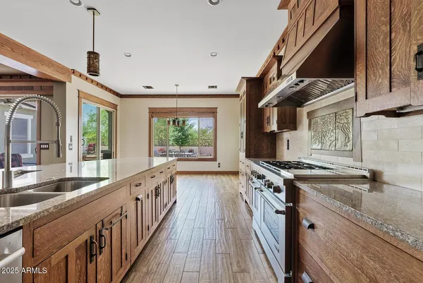 a kitchen with stainless steel appliances granite countertop a sink a stove and a wooden floors