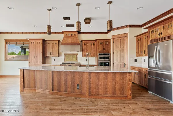 a kitchen with stainless steel appliances granite countertop a refrigerator a oven and white cabinets with wooden floors