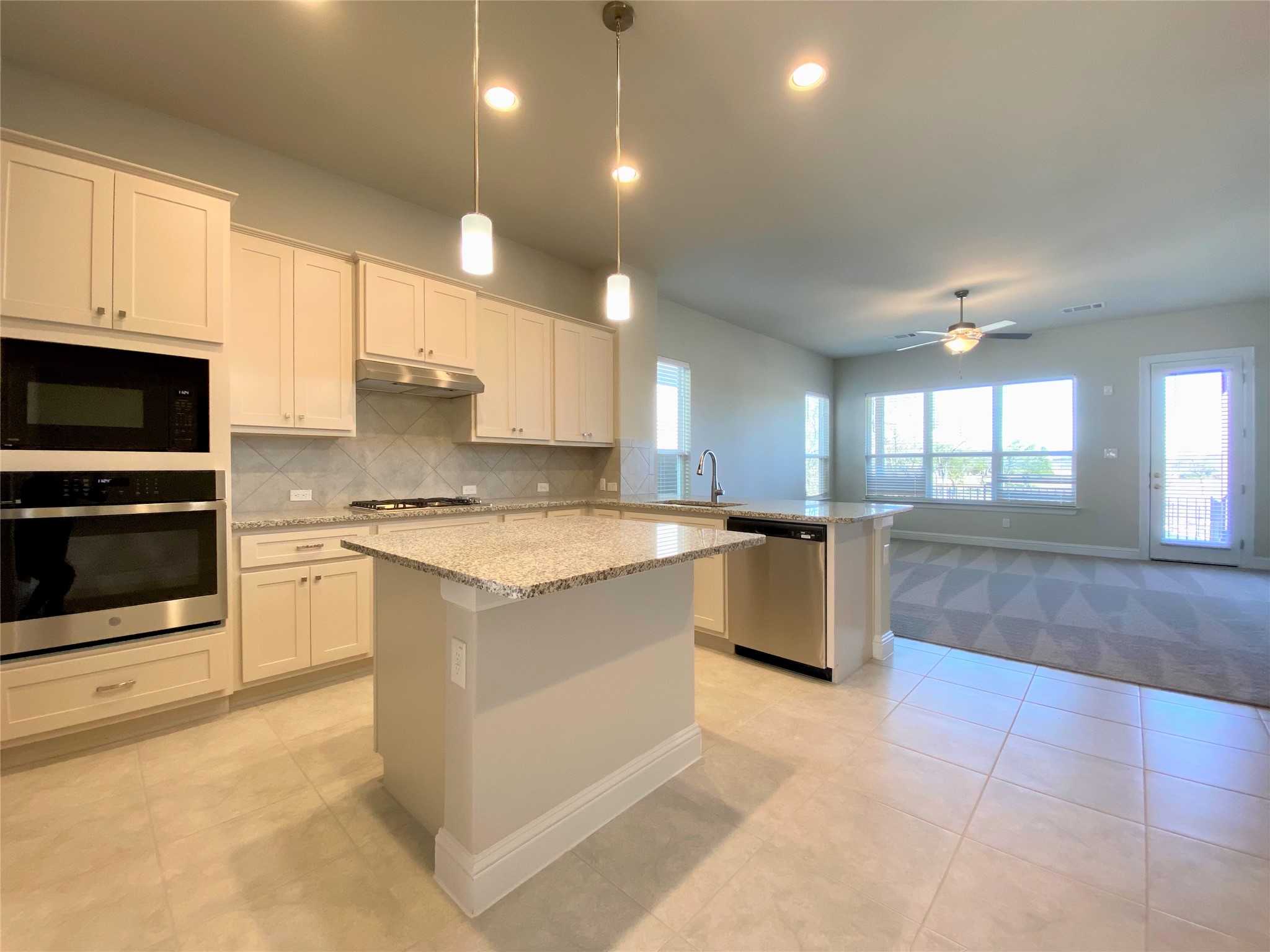 600 C-Bar Ranch Trail, Unit 105 Cedar Park, TX 78613 - Photo 3 of 12 Kitchen with appliances with stainless steel finishes, decorative light fixtures, white cabinets, light stone counters, and a peninsula