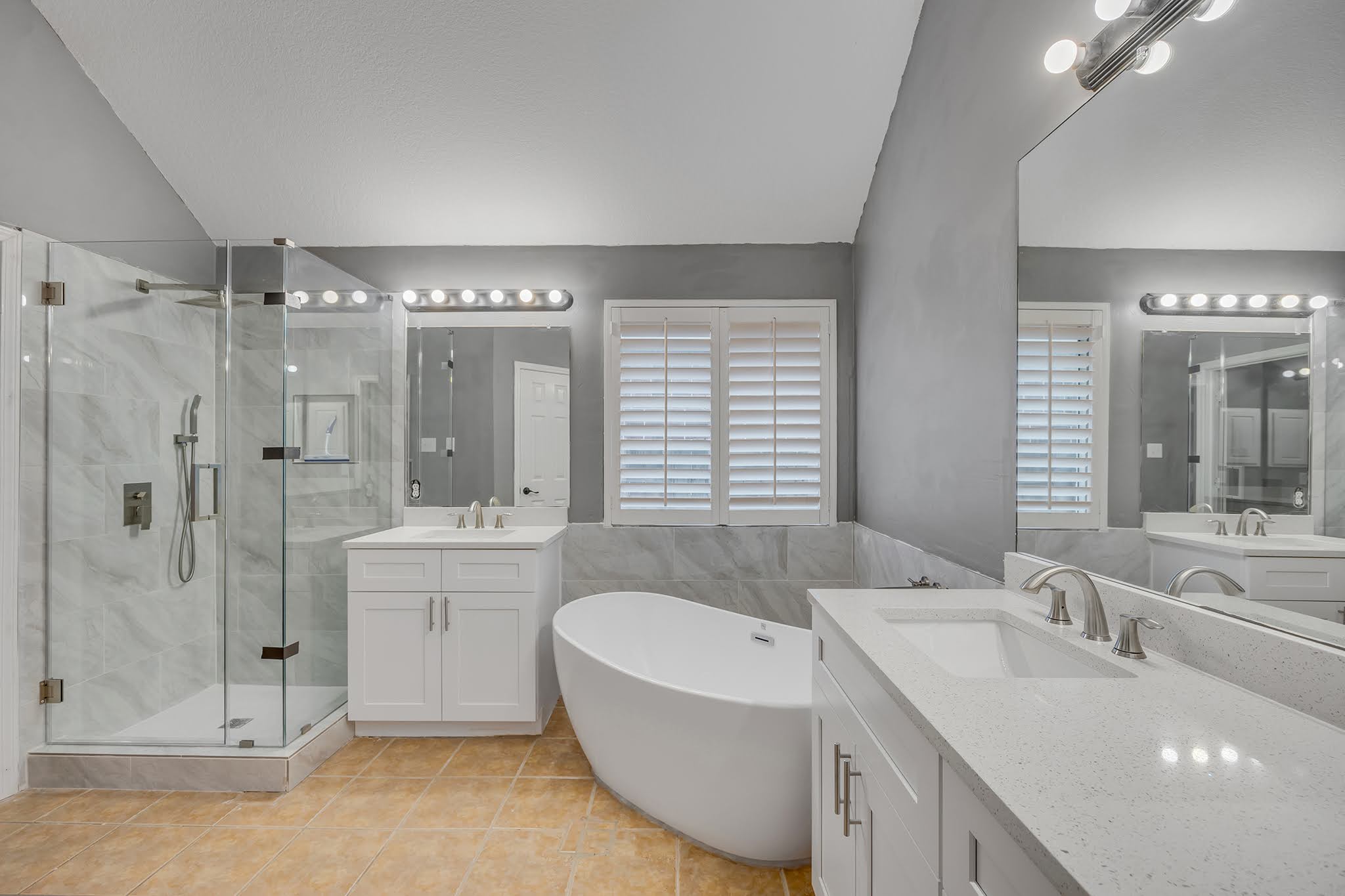 2726 Grimes Ranch Road Austin, TX 78732 - Photo 31 of 35 Bathroom featuring a freestanding bath, vaulted ceiling, two vanities, a marble finish shower, and tile walls