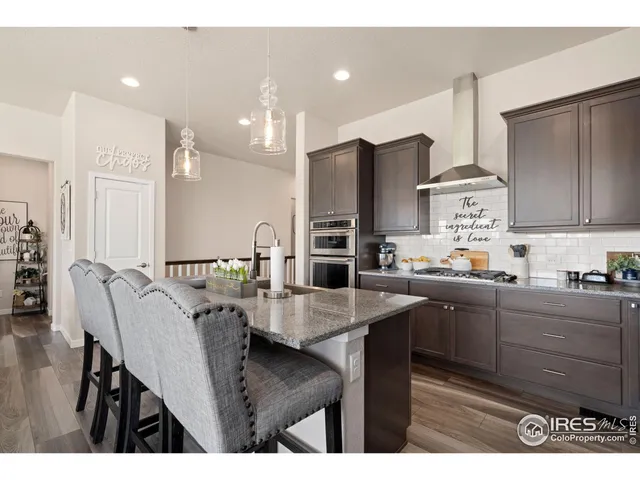 a kitchen with stainless steel appliances kitchen island granite countertop a table chairs microwave and sink