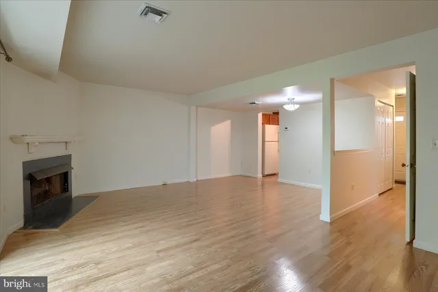 a view of empty room with wooden floor and fireplace