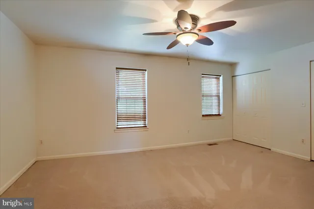 an empty room with a window and a ceiling fan