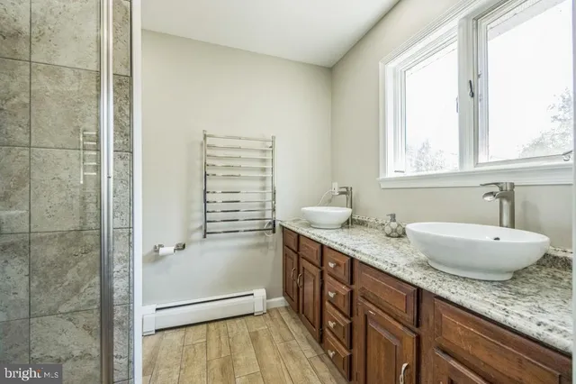 a bathroom with a granite countertop sink a mirror and a shower