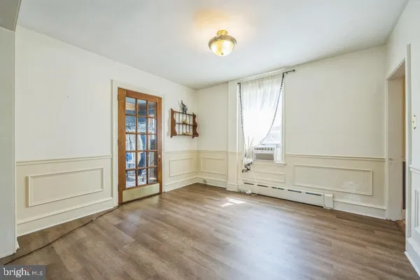 an empty room with wooden floor cabinet and windows
