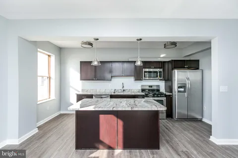 a large kitchen with stainless steel appliances granite countertop a stove a sink and a refrigerator