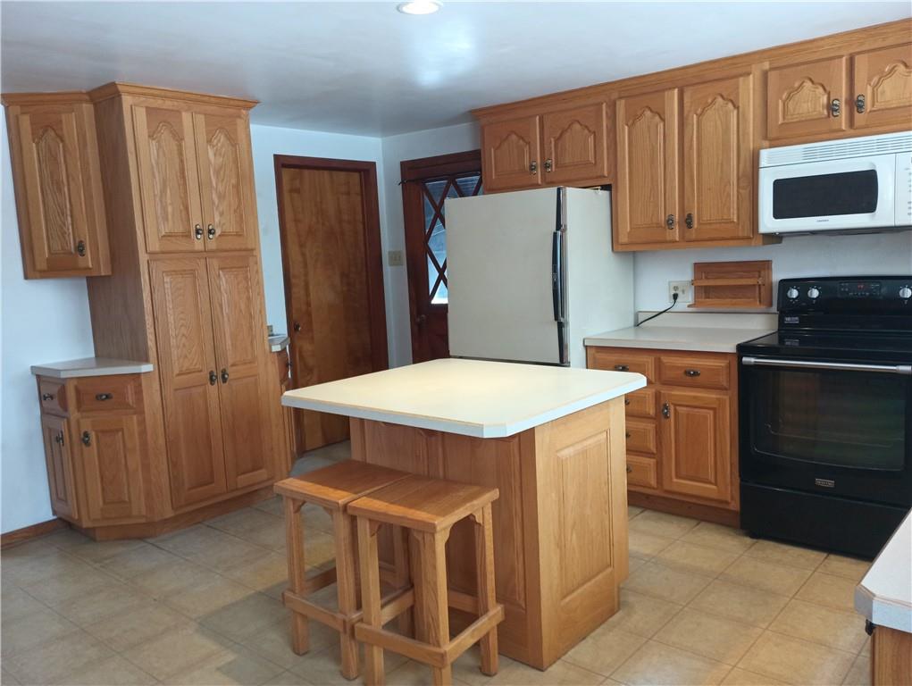 234 Baker Road Greenville, PA 16125 - Photo 5 of 16 a kitchen with a refrigerator a stove and wooden cabinets