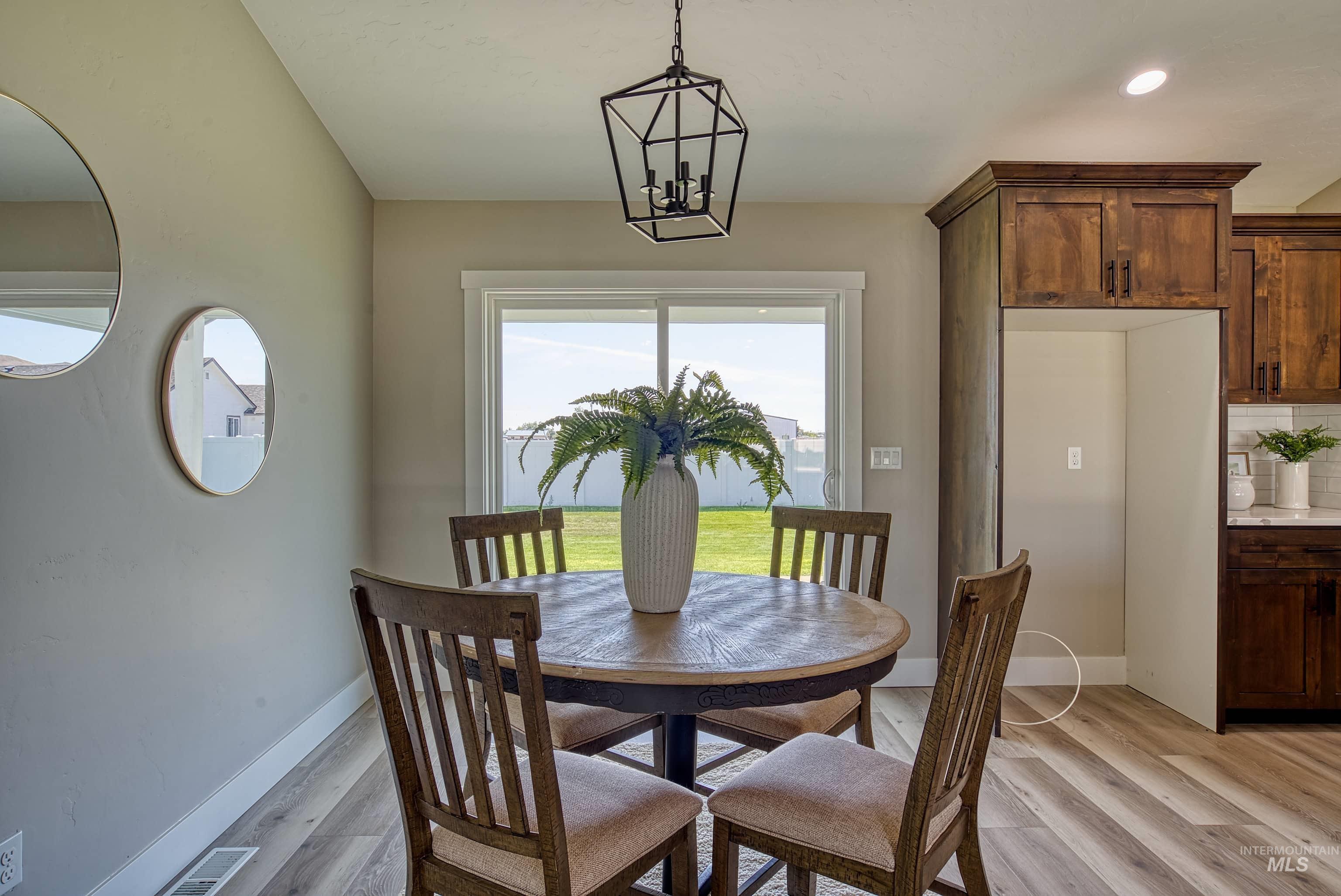 960 Campbell Street Vale, OR 97918 - Photo 12 of 49 Dining area featuring a contemporary geometric pendant light fixture, wood-finish flooring, and a sliding glass door providing backyard access