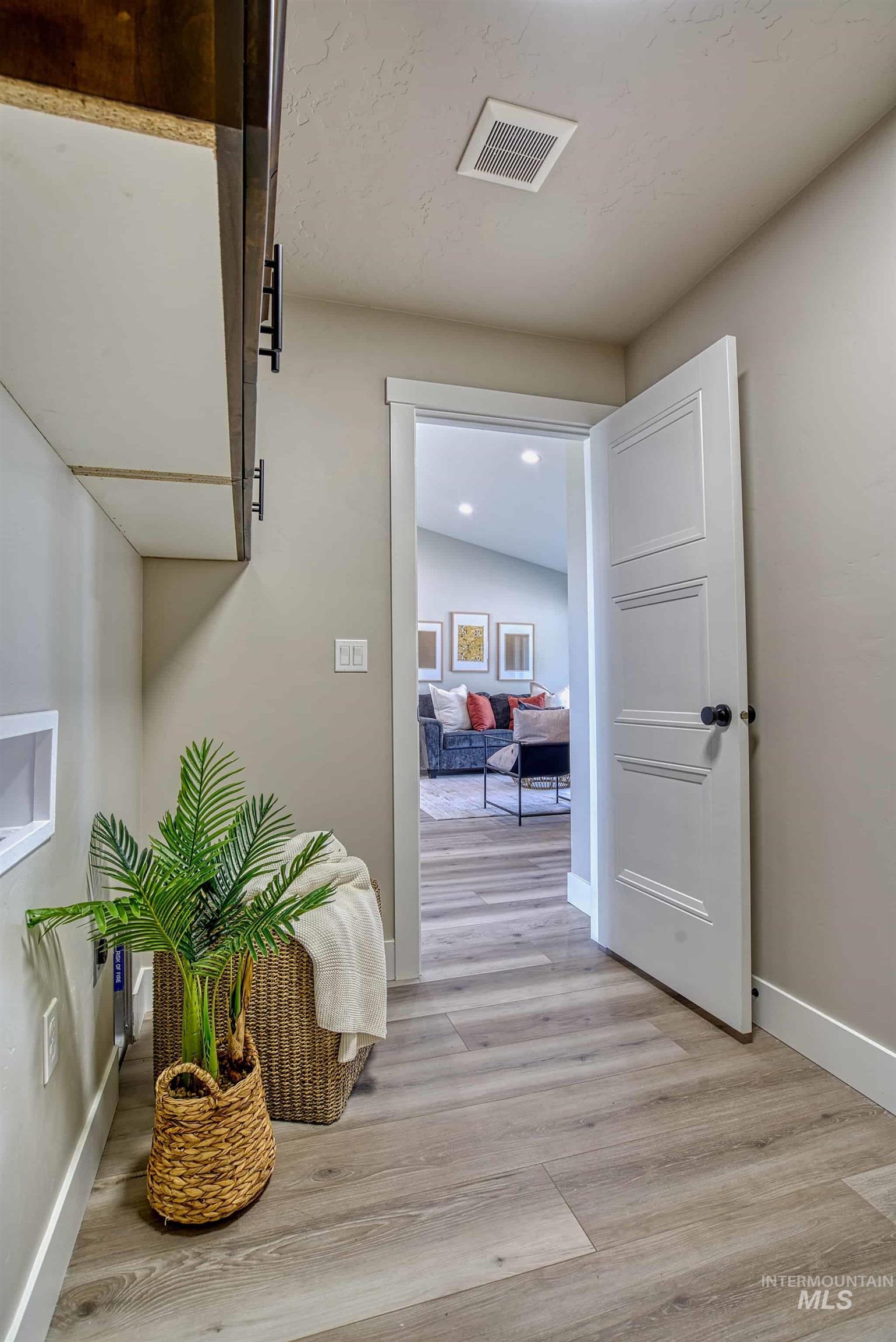 960 Campbell Street Vale, OR 97918 - Photo 16 of 49 Utility area featuring a built-in dark wood-finish cabinet with matte black hardware, light neutral wall paint, and wide-plank wood-finish flooring