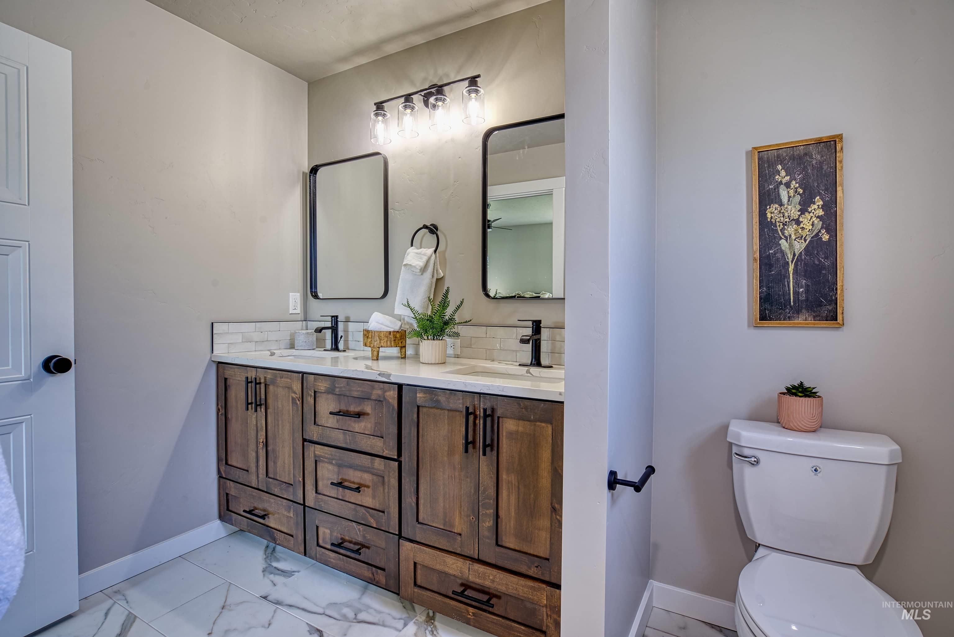 960 Campbell Street Vale, OR 97918 - Photo 24 of 49 Double vanity featuring wood-finish cabinetry, white countertops, dual sinks with matte black fixtures, and framed mirrors