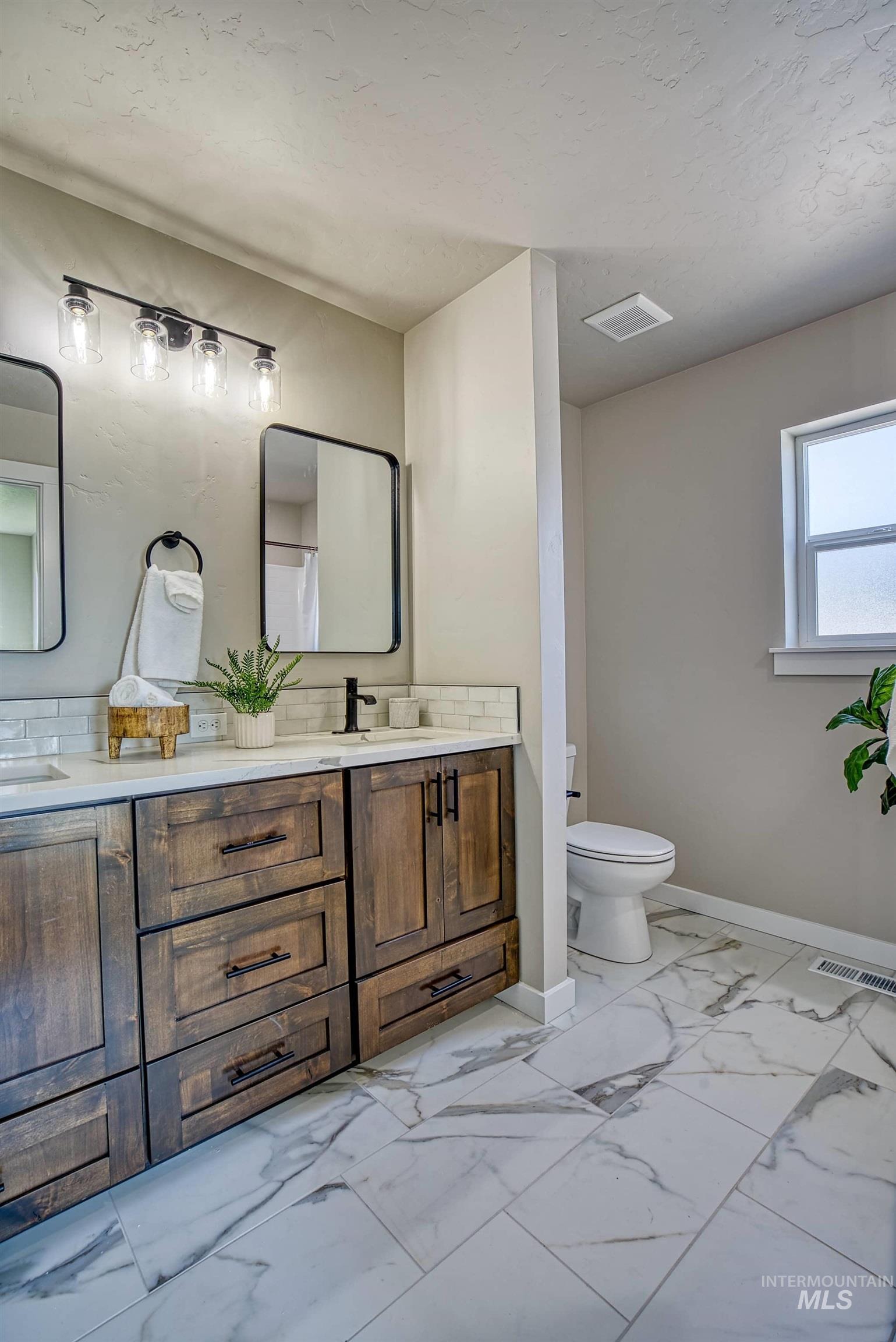 960 Campbell Street Vale, OR 97918 - Photo 27 of 49 Bathroom featuring a dual vanity with wood-finish cabinetry, white countertops, and subway tile backsplash
