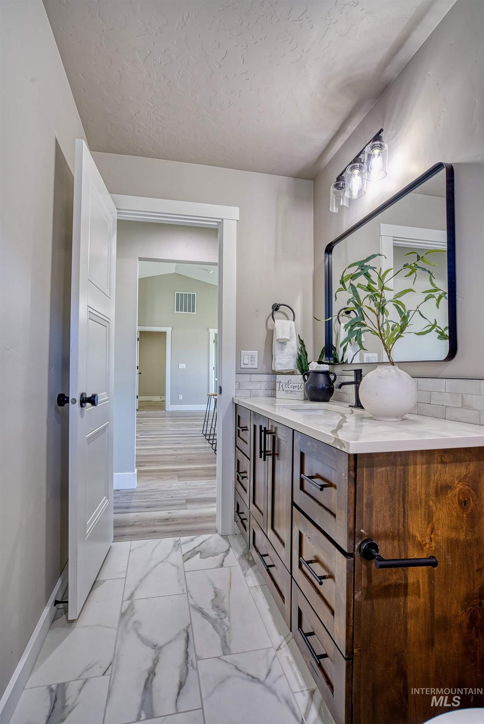 960 Campbell Street Vale, OR 97918 - Photo 29 of 49 Bathroom vanity featuring a dark wood cabinet with black hardware, a white countertop, and a subway tile backsplash