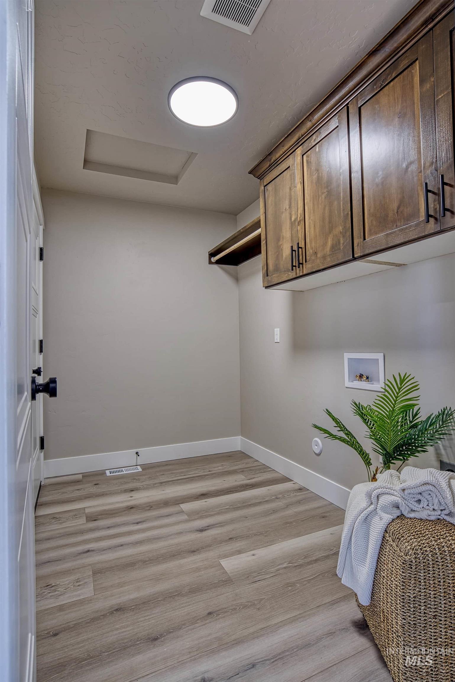 960 Campbell Street Vale, OR 97918 - Photo 34 of 49 Dedicated utility space featuring wood-finish flooring, dark wood cabinetry with matte black hardware, and a round flush-mount ceiling light