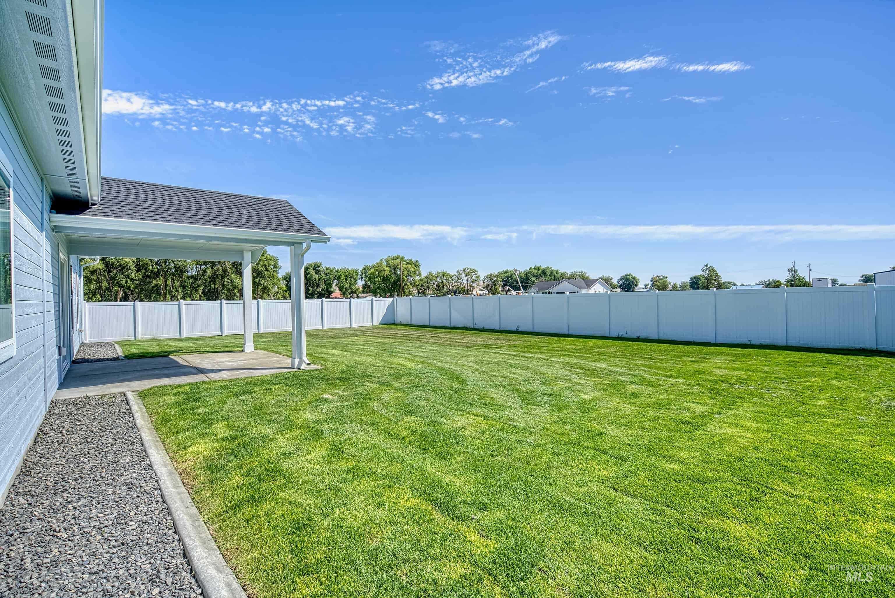 960 Campbell Street Vale, OR 97918 - Photo 48 of 49 Expansive green lawn with a covered patio, vinyl fencing, gravel border, and light blue siding