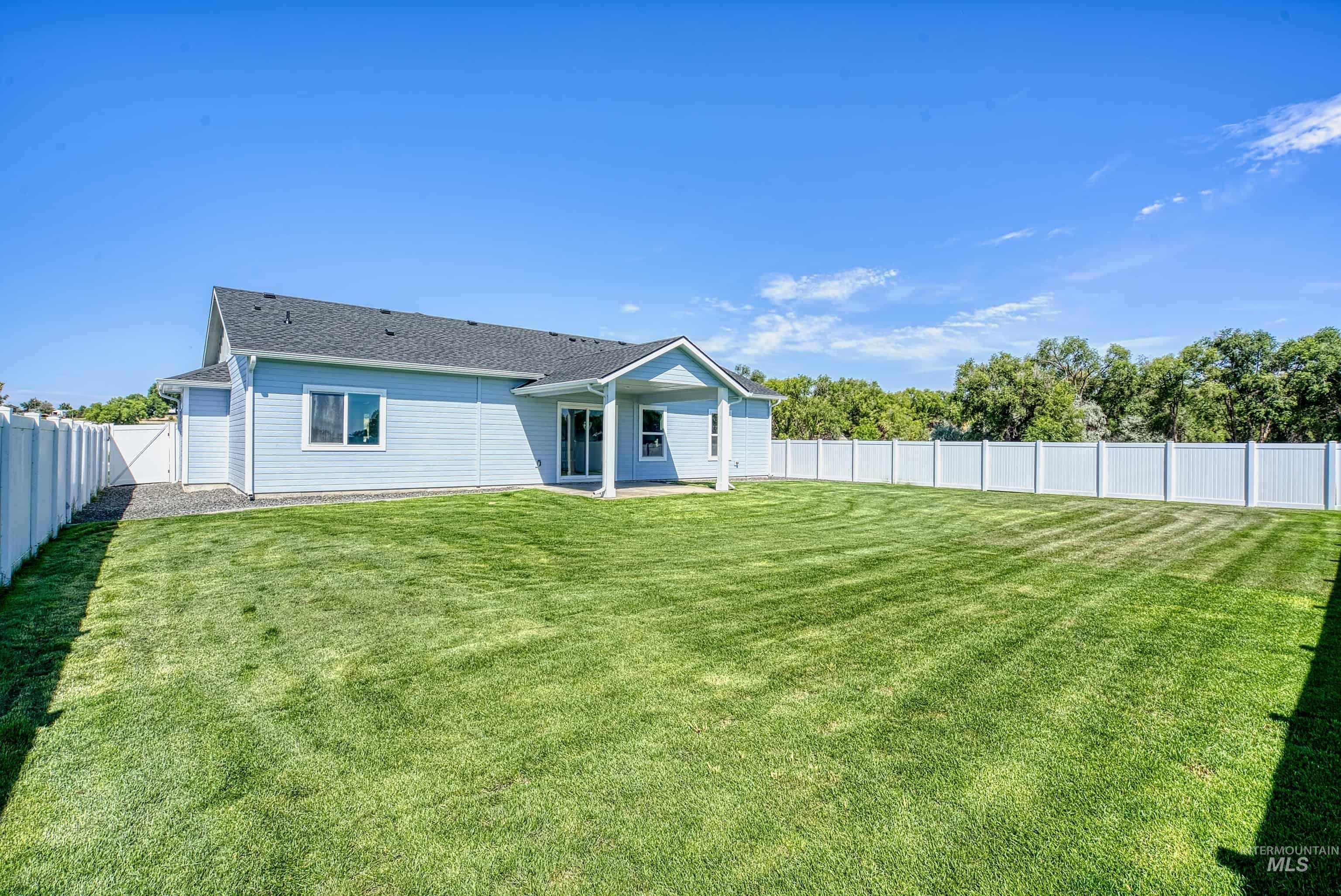 960 Campbell Street Vale, OR 97918 - Photo 49 of 49 Spacious backyard featuring a manicured lawn, a full white vinyl privacy fence, and a covered patio area with direct access to the interior
