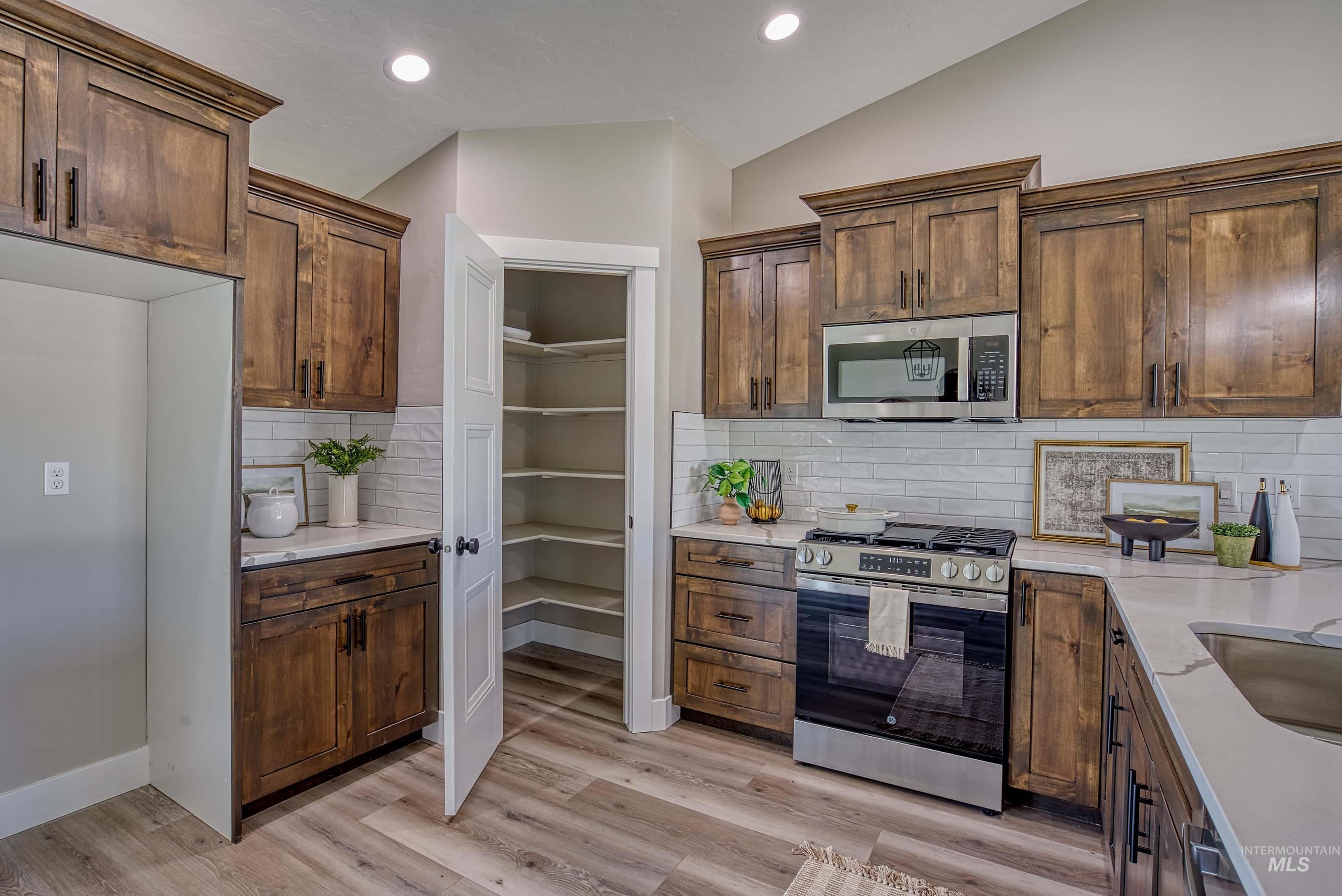 960 Campbell Street Vale, OR 97918 - Photo 6 of 49 Kitchen featuring wood-finish cabinetry, light-toned countertops, subway tile backsplash, stainless steel appliances, and a walk-in pantry with built-in shelving