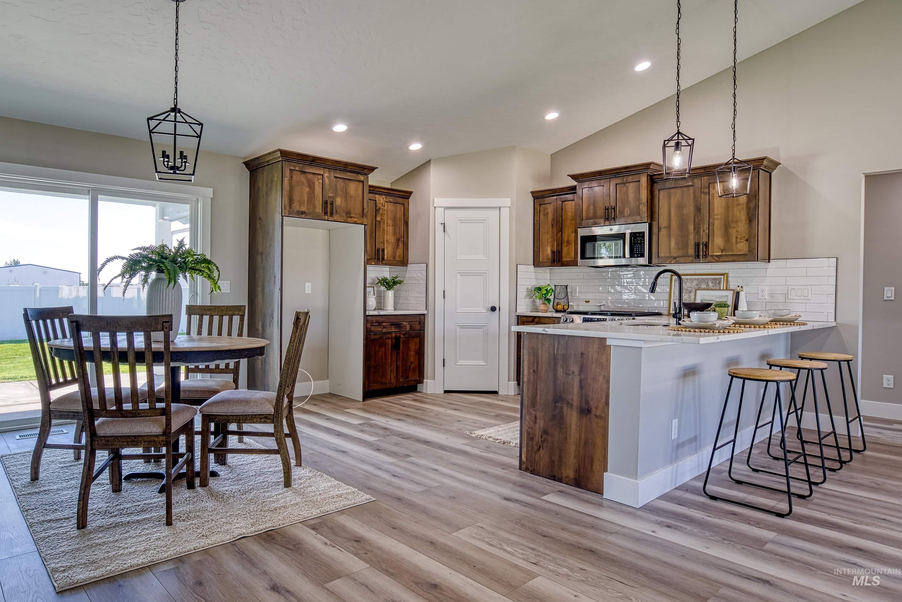 960 Campbell Street Vale, OR 97918 - Photo 7 of 49 Kitchen with wood-finish flooring, dark wood cabinetry, white subway tile backsplash, and a central island featuring a quartz countertop