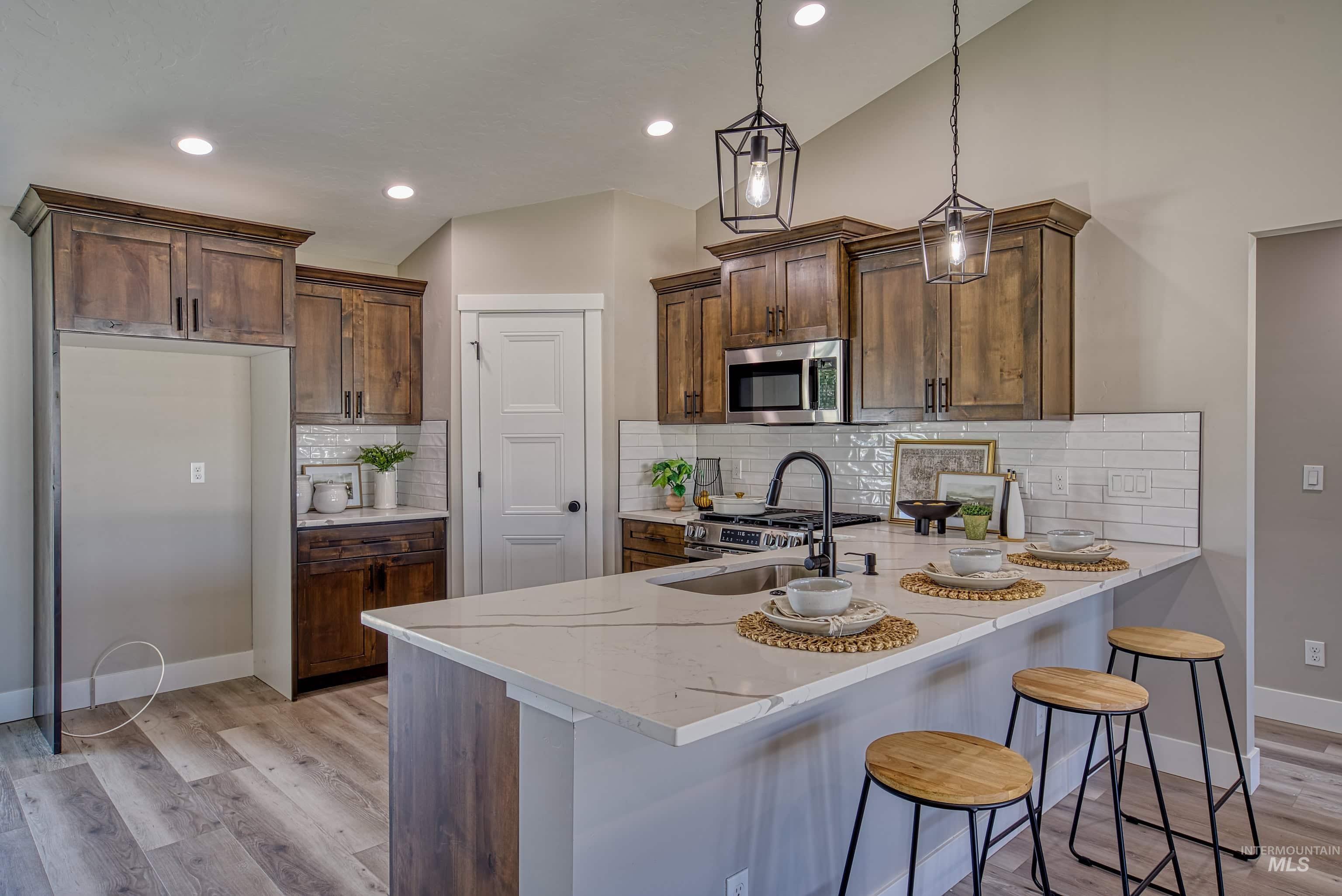 960 Campbell Street Vale, OR 97918 - Photo 8 of 49 Kitchen featuring a quartz-topped island with seating, stainless steel appliances, wood-finish cabinetry, and recessed lighting