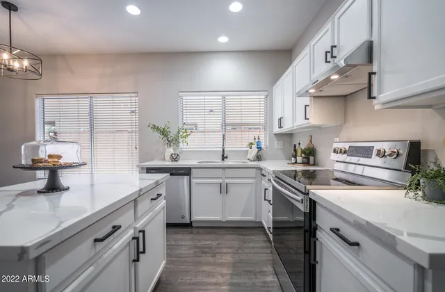 a kitchen with a sink dishwasher a stove and white cabinets