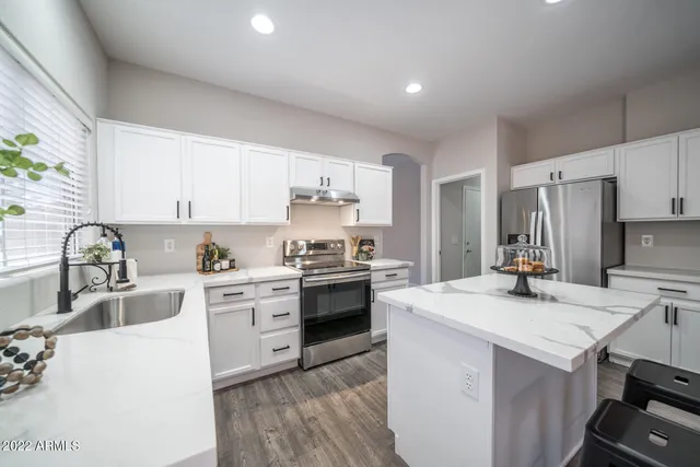 a kitchen with a stove a sink dishwasher a refrigerator and white cabinets with wooden floor