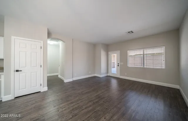 a view of an empty room with wooden floor and window