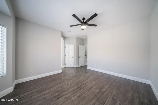an empty room with wooden floor and a ceiling fan