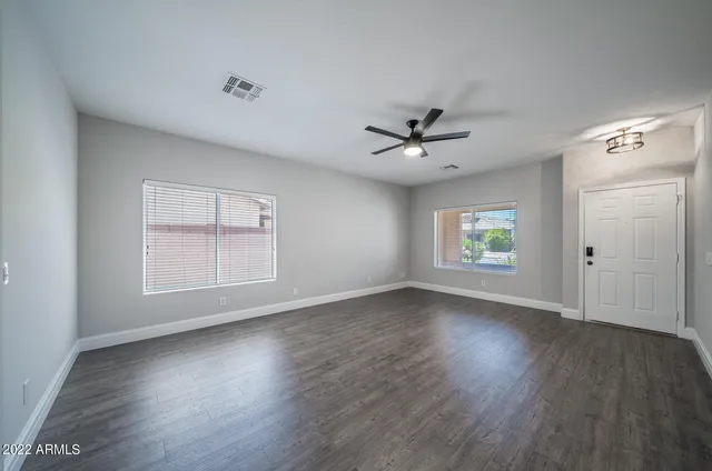 a view of an empty room with a window and wooden floor