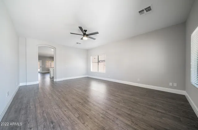 a view of an empty room with a window and wooden floor