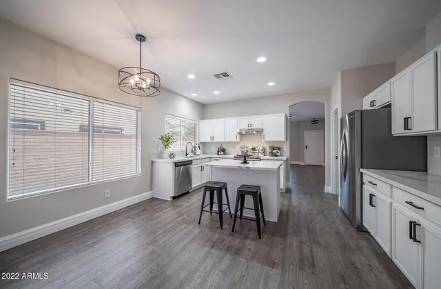 a open kitchen with stainless steel appliances granite countertop a stove refrigerator and a dining table with wooden floor