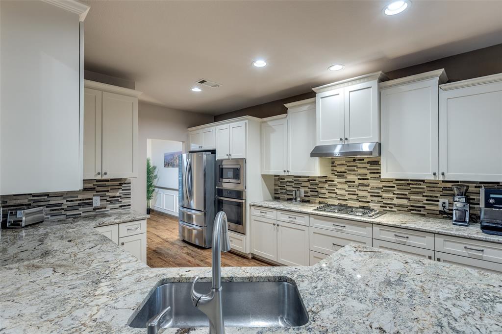 1445 Stagecoach Way Frisco, TX 75033 - Photo 15 of 39 a kitchen with stainless steel appliances granite countertop a sink stove and refrigerator
