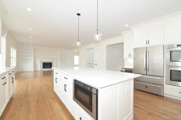 a large kitchen with stainless steel appliances kitchen island a large counter top a sink a refrigerator and a fireplace