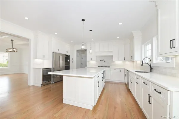 a large white kitchen with stainless steel appliances lots of counter space and wooden floor