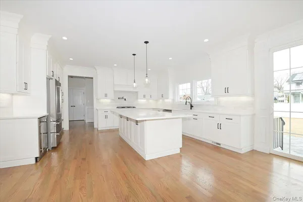 a large white kitchen with a stove a sink dishwasher and a refrigerator with wooden floor