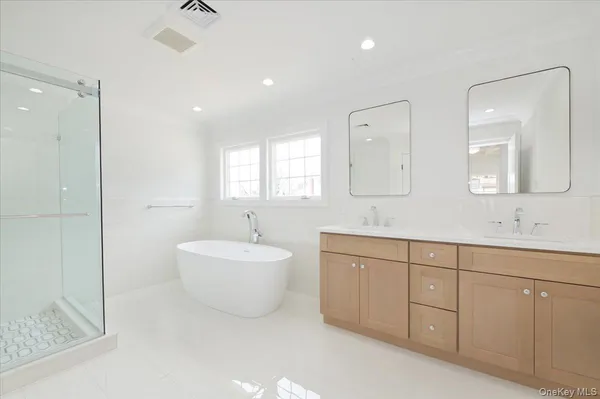 a spacious bathroom with a double vanity sink mirror and bathtub