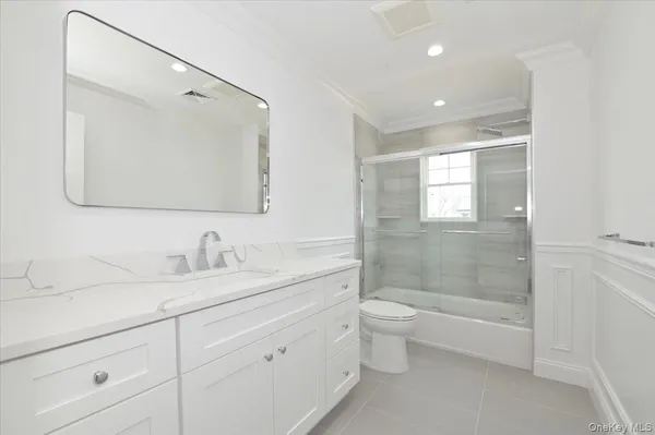 a bathroom with a double vanity sink toilet mirror and shower