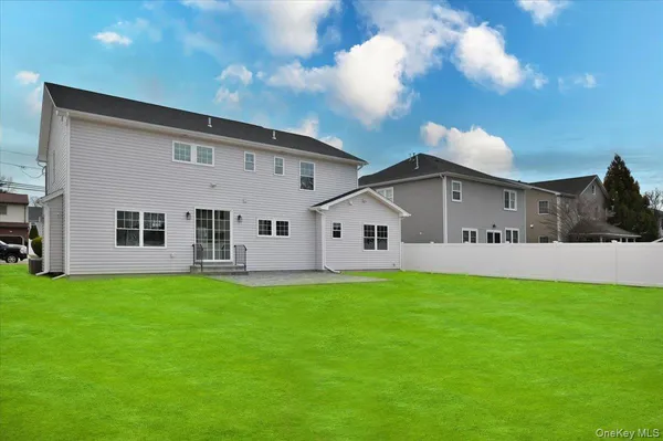a view of a white house in front of a big yard with large trees