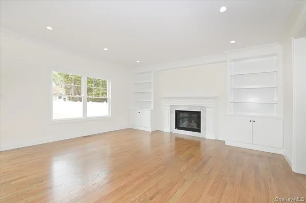 an empty room with wooden floor a fireplace and windows