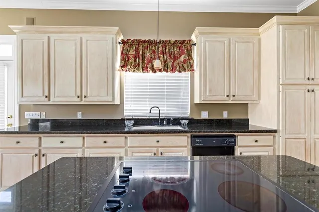 a kitchen with granite countertop a sink a stove and cabinets