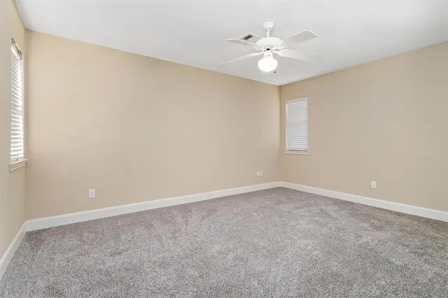 an empty room with windows and ceiling fan