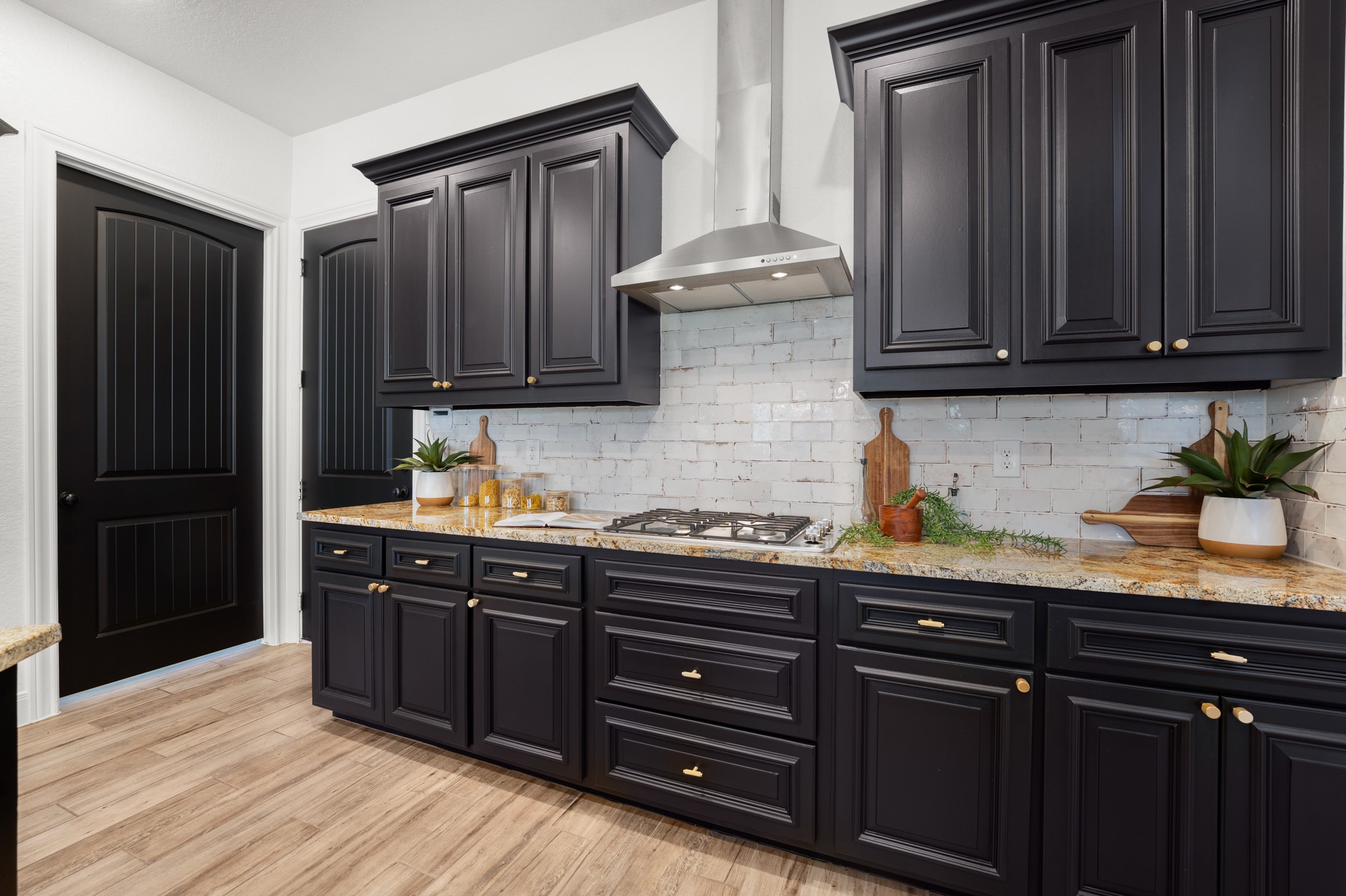 128 Hiram Cook Blanco, TX 78606 - Photo 5 of 40 Kitchen featuring dark cabinetry, light-toned countertops, a gas range with a stainless steel range hood, a white subway tile backsplash, and wood-finish flooring