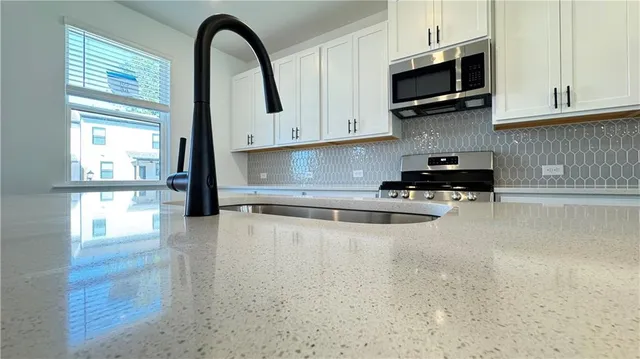 a kitchen with stainless steel appliances granite countertop a stove a sink and a microwave