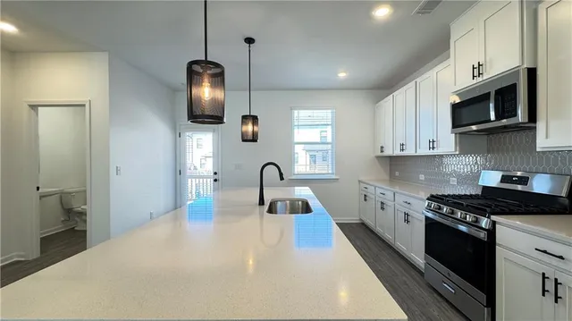 a kitchen with stainless steel appliances granite countertop a sink a stove and a refrigerator