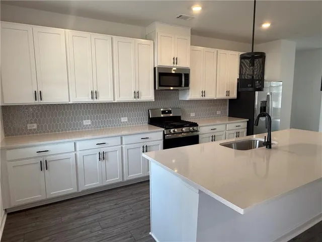 a kitchen with kitchen island granite countertop stainless steel appliances stove microwave and sink