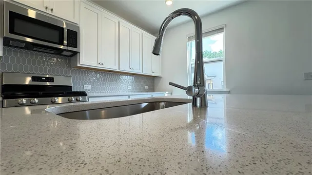 a kitchen with stainless steel appliances granite countertop a sink a stove top oven and granite counter tops
