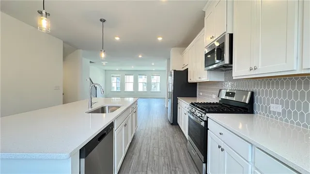 a kitchen with stainless steel appliances granite countertop a sink a stove and a wooden floors