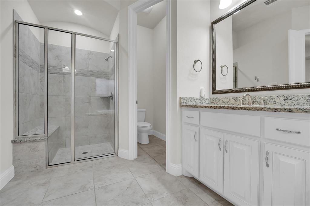 1011 Prairie Ridge Lane Arlington, TX 76005 - Photo 32 of 32 Spacious bathroom featuring a glass-enclosed shower with tile surround and built-in bench