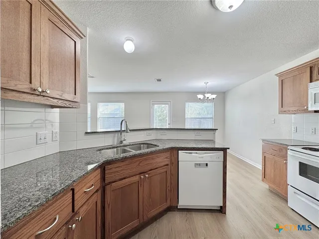 a kitchen with granite countertop stainless steel appliances a sink stove and cabinets