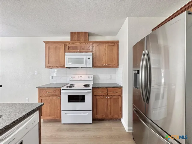 a kitchen with stainless steel appliances granite countertop a refrigerator stove and sink