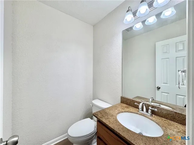 a bathroom with a granite countertop sink a toilet and a mirror
